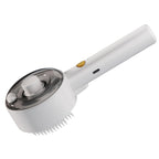 White spray pet grooming comb angled to show the round reservoir head, handle controls, and grooming pins.