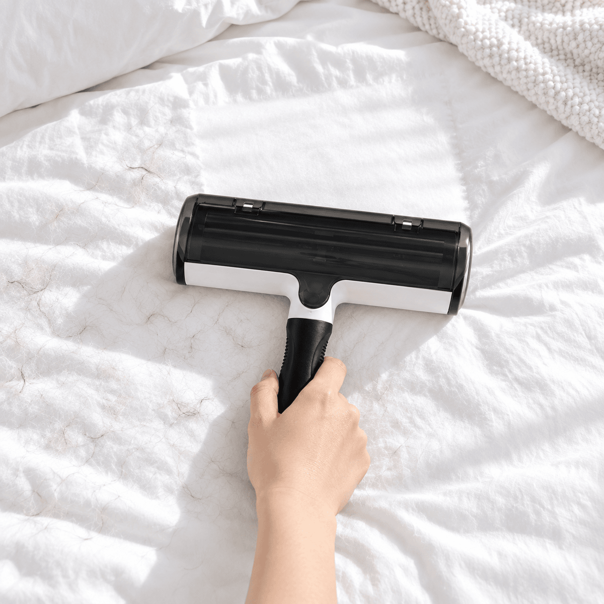 Reusable pet hair roller removing loose fur from white bedding